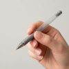 Bolígrafo gris con cuerpo transparente sostenido en una mano