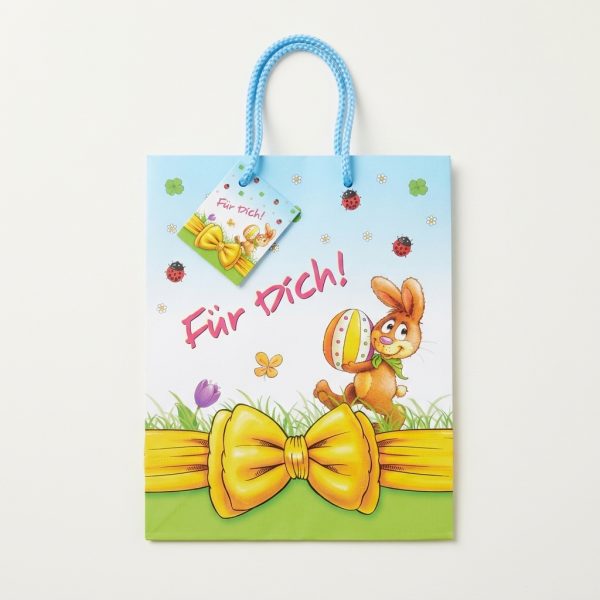 Bolsa de regalo de Pascua extendida con asas azules y tarjeta a juego.