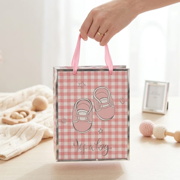 Bolsa de regalo rosa con dibujos de patucos sostenida por sus asas de cinta