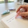 Corrector de cinta rosa en uso sobre cuaderno
