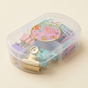Estuche de clips pastel visto en ángulo Vista en ángulo del estuche translúcido de tres compartimentos con clips y pinzas pastel