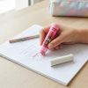 Mano usando una goma Barbie x Maped para borrar en un cuaderno