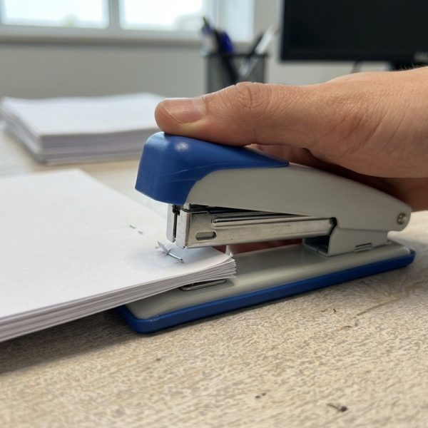 Mano utilizando una grapadora de sobremesa azul y blanca