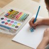 Mano coloreando un dibujo con un lápiz azul junto al maletín Play-Doh abierto