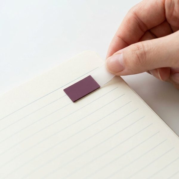 Mano colocando un marcapáginas adhesivo en la página de un cuaderno