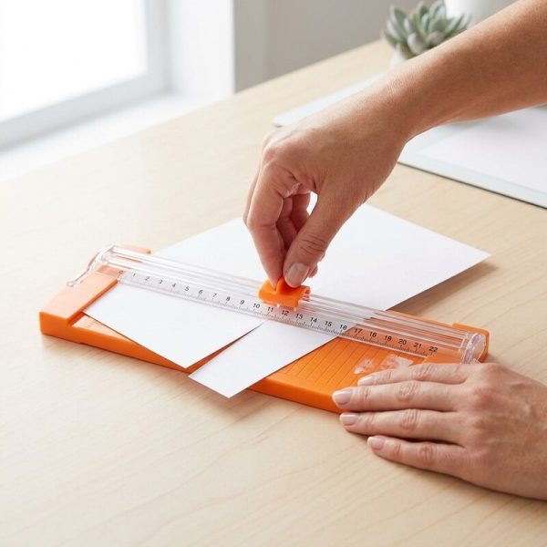 Persona adulta cortando papel con una mini cizalla A5 naranja