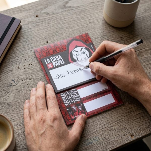 Persona escribiendo en el bloc de notas adhesivas La Casa de Papel con dos tiras.