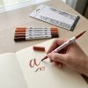 Seis rotuladores de doble punta en tonos tierra: ejemplo de lettering