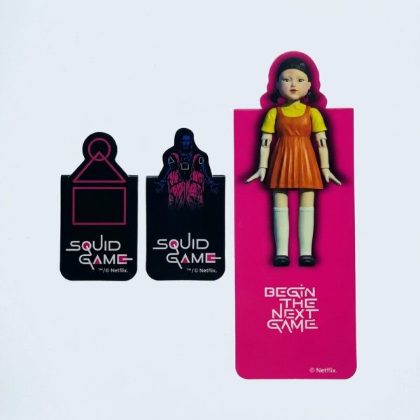 Tres marcapáginas de Squid Game: dos pequeños negros y uno alargado rosa con ilustración de la muñeca.