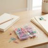 Recipiente transparente abierto con accesorios de escritorio pastel junto a cuadernos y documentos
