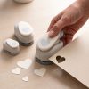 Mano usando una troqueladora Rayher para recortar corazones enteros de papel