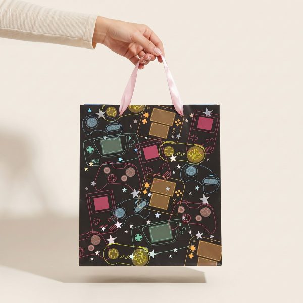 Bolsa de regalo gamer con asas de cinta rosa sostenida en una mano