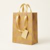 Bolsa de regalo kraft con arcoíris amarillos y asas doradas, vista lateral
