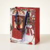Bolsa de regalo navideña con muñeco de nieve y puerta roja, vista en tres cuartos con lateral rojo visible.