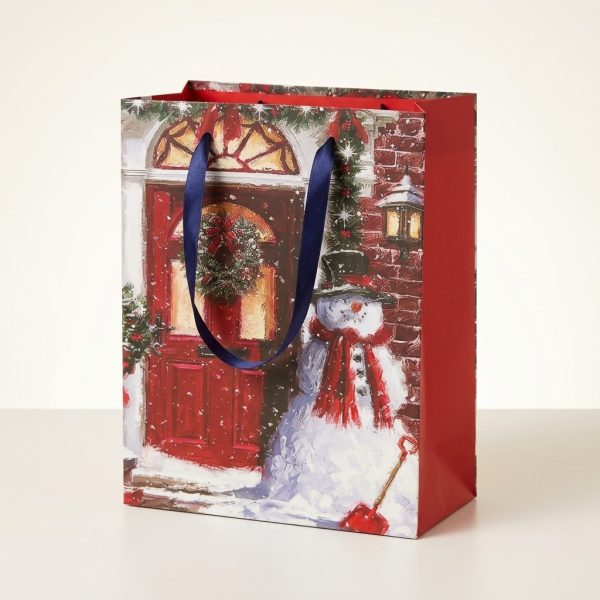 Bolsa de regalo navideña con muñeco de nieve y puerta roja, vista en tres cuartos con lateral rojo visible.