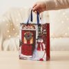 Bolsa de regalo navideña con muñeco de nieve y puerta roja preparada para entregar, con papel de seda decorativo no incluido.
