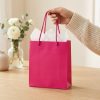bolsa-regalo-rosa-fucsia-lisa-en-uso Bolsa de regalo rosa fucsia lisa con asas de cordón, en uso con papel de seda decorativo