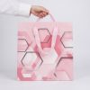 Bolsa de regalo rosa geométrica sostenida por sus asas