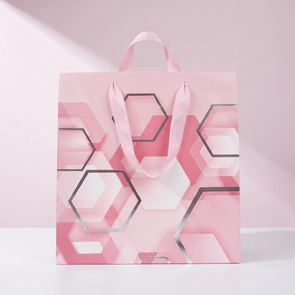 Bolsa geométrica rosa de regalo sobre fondo rosa suave