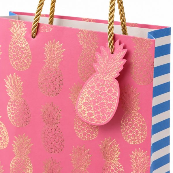 Bolsa de regalo rosa con piñas doradas, detalle del estampado y las asas
