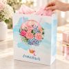 Bolsa de regalo con globo floral y asas rosas, bolsa en uso con papel de seda decorativo