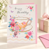 Tarjeta de cumpleaños Taza con flores junto a un regalo