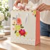 Bolsa de regalo floral con borde ondulado dorado y lateral rosa — en uso